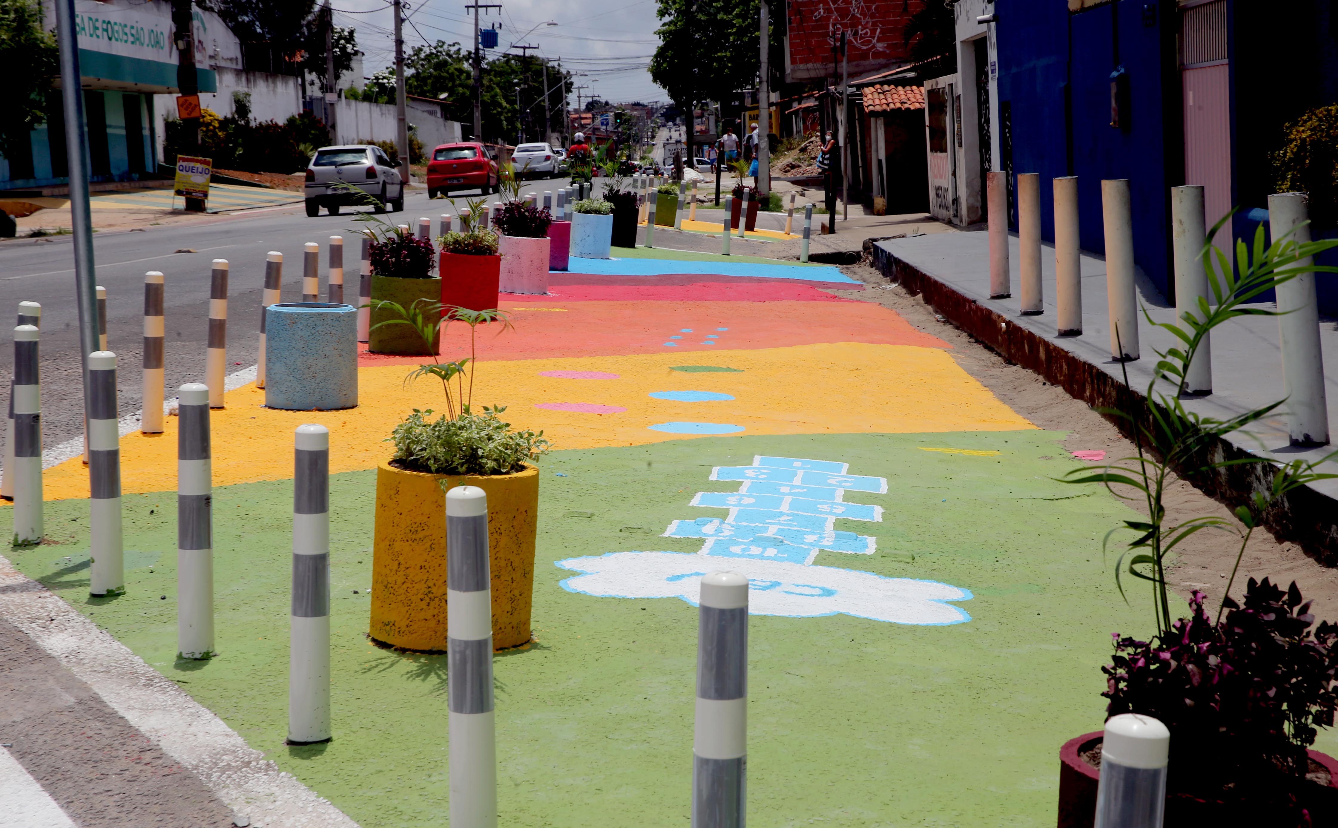 a foto mostra o projeto praça viva que pinta o asfalto de algumas vias e coloca mobiliário urbano, como bancos e jarros de plantas